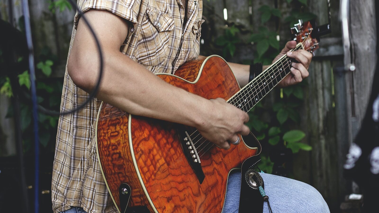 person holding brown guitar outdoor
